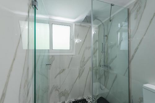 a bathroom with a glass shower with a window at Splash of Glam II 10 Steps from Acropolis in Athens