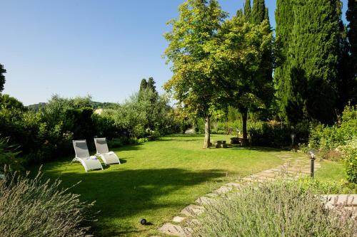 two white chairs sitting in the grass in a garden at Roveta Apartment in Scandicci