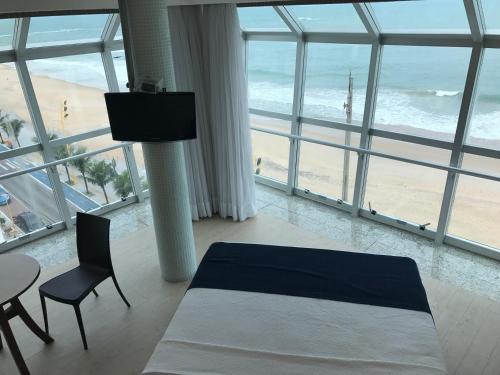 a bedroom with a bed and a table and a view of the beach at Hotel Brisa Tropical De Macaé in Macaé