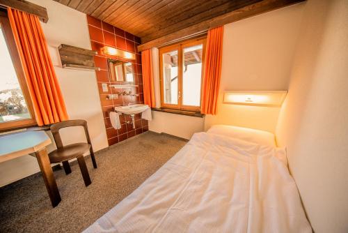 a small room with a bed and a desk and a table at Sportchalet Mürren in Mürren