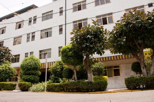 a white building with trees in front of it at HOTEL ESTADIO S.A in Mexico City