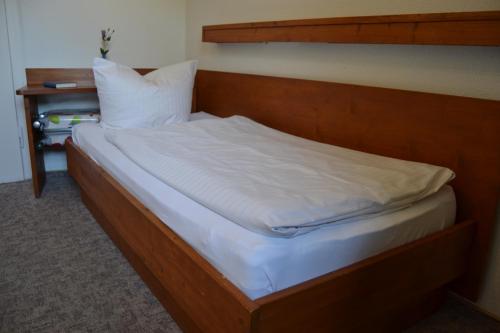 a bed with white sheets and a wooden headboard at Hofreit am Bierkeller in Kehl am Rhein