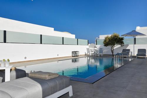 a swimming pool with a bed and chairs on a building at Tramonto Private Villa in Monolithos