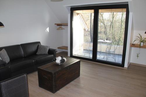 a living room with a black couch and a table at Logies Tommenmolen in Grimbergen