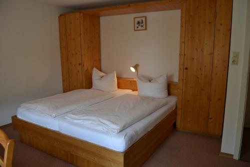 a bedroom with a wooden bed with white sheets and pillows at Hofreit am Bierkeller in Kehl am Rhein