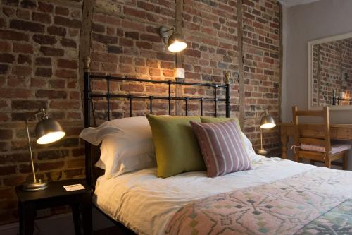 um quarto com uma cama e uma parede de tijolos em The Crown Aldbourne em Aldbourne