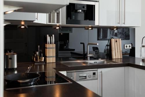 a kitchen with white cabinets and a black counter top at Luxoise Apartments in Berlin