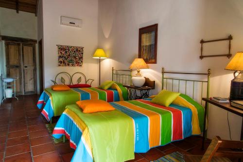 um quarto com 3 camas e len��is coloridos em Quinta dos Trevos - Artes e Of�cios em Ladoeiro