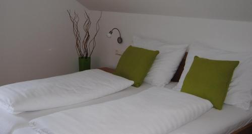 a white bed with two green pillows on it at Weingut Schlafgut Genussgut Lorenz in Kitzeck im Sausal