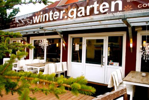 斯拉德明的住宿－Hotel Wintergarten，餐厅前面设有白色的桌椅