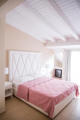 a white bedroom with a large bed with pink sheets at Attico in Canicattì