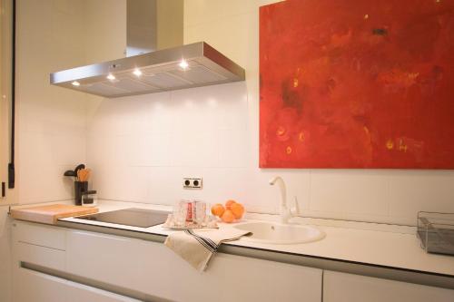 eine Küche mit einem Waschbecken und einem roten Gemälde in der Unterkunft Toreros de Sevilla 5 pax in Sevilla