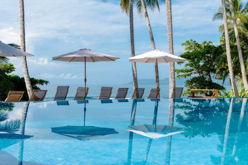 a swimming pool with chairs and umbrellas and the ocean at Tango Mar Beachfront Boutique Hotel & Villas in Tambor