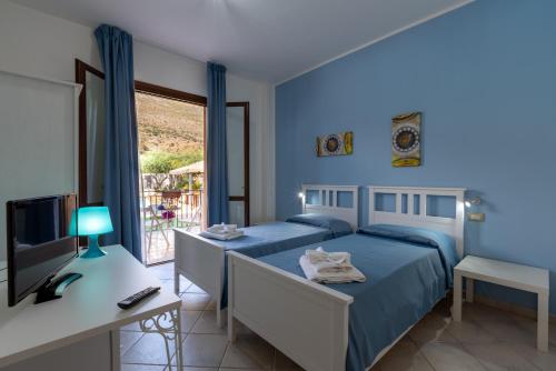 1 Schlafzimmer mit 2 Betten, einem Schreibtisch und einem TV in der Unterkunft Hotel Achibea in San Vito lo Capo