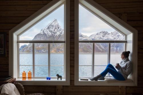 a man sitting on a bench in front of a window at Olstind in Sakrisøy in Reine