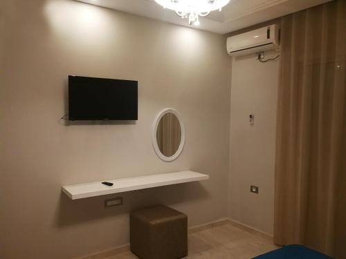 a room with a tv on the wall and a stool at London House in Bizerte