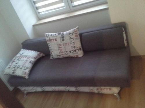 a couch with two pillows and a window at Apartamenty Górskie LĄDEK-ZDRÓJ in Lądek-Zdrój