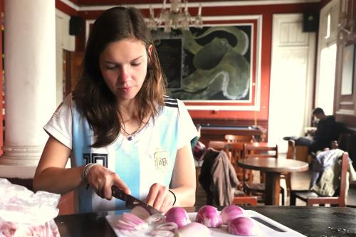 a woman cutting up onions on a table at 1900 Backpacker's Hostel in Lima
