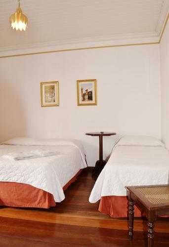 a bedroom with two beds and a table in it at Pousada Solar Nossa Senhora Das Merces in Ouro Preto