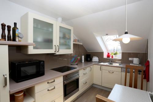 a kitchen with white cabinets and a black microwave at Vechteblick in Schüttorf