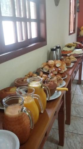ein Tisch mit Tellern voller Donuts und Gläsern Orangensaft in der Unterkunft Pousada Caminho da Serra in Tiradentes
