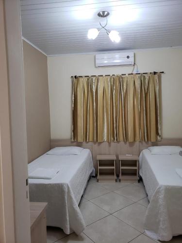 a room with two beds and a window at Felipe Family Houses - Casas de temporada in Foz do Iguaçu
