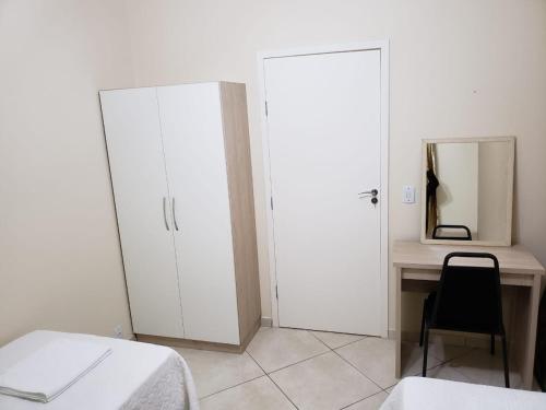 a white bedroom with a desk and a mirror at Felipe Family Houses - Casas de temporada in Foz do Iguaçu