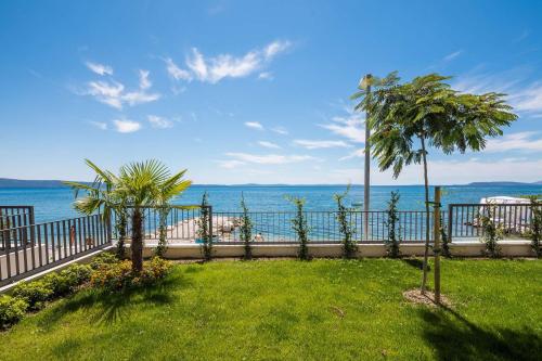 a fence with palm trees next to the water at Villa Four Brothers - Middle Floor in Podstrana