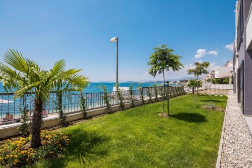 a garden with palm trees and the ocean in the background at Villa Four Brothers - Middle Floor in Podstrana