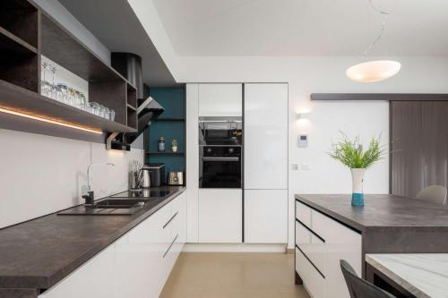 a kitchen with white cabinets and a black counter top at Villa Four Brothers - Middle Floor in Podstrana
