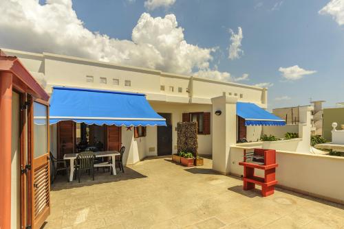 a patio with blue umbrellas and a table and chairs at Panoramici Monolocali in Leuca