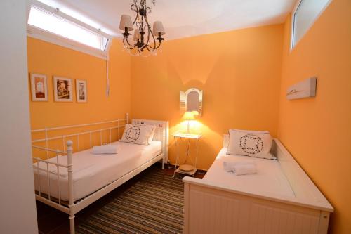 2 Betten in einem Zimmer mit orangefarbenen Wänden und einem Kronleuchter in der Unterkunft Villa Blue in Skala Potamias