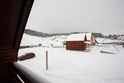 a car parked in a snow covered yard with a barn at Family Apartments in Žabljak