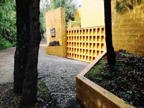 a yellow building with a fence and two trees at Hotel Casa en el Campo in Morelia