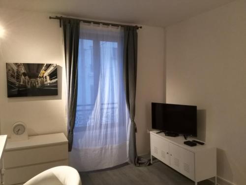 ein Wohnzimmer mit einem großen Fenster und einem TV in der Unterkunft Comfy Parisian studio! in Ivry-sur-Seine