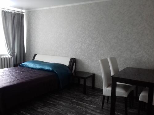 ブリャンスクにあるАпартаменты в центре на Авиационной 19のベッドルーム1室(ベッド1台、テーブル、椅子付)