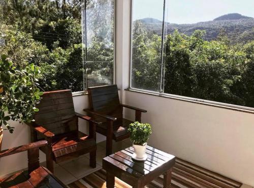 two chairs and a table in a room with a window at Hotel Guaporé - Campo Bom RS in Campo Bom