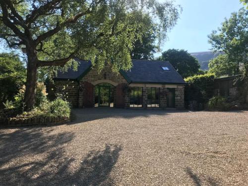 a stone house with a tree and a driveway at The Old Winery Loft in Edale