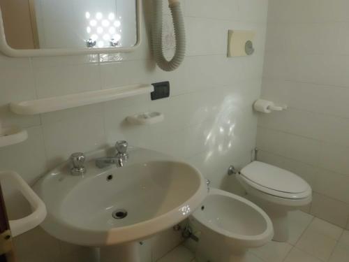 a white bathroom with a sink and a toilet at Hotel Paolina in Viareggio
