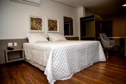a bedroom with a large bed with a white comforter at Grand Café Hotel in Manhuaçu