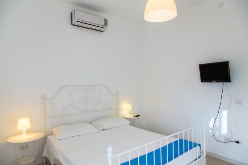 1 dormitorio blanco con 1 cama blanca y TV en Jazira en Scoglitti