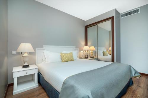 - une chambre avec un grand lit blanc et un miroir dans l'établissement Gaia Residence, à Vila Nova de Gaia