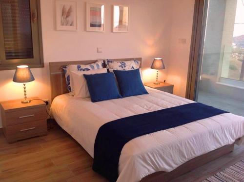 a bedroom with a large bed with blue pillows at Menies Mediterranean Heights in Parekklisha