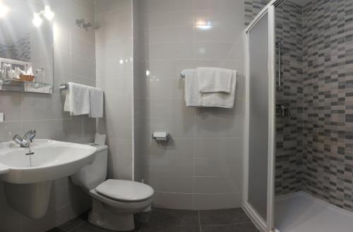 a bathroom with a toilet and a sink and a shower at Hotel Bonaire in Revolta
