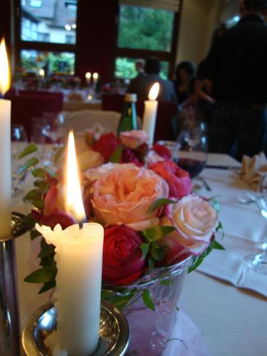 a table with two candles and a vase of roses at Hotel Restaurant Paradeismühle in Klingenberg am Main