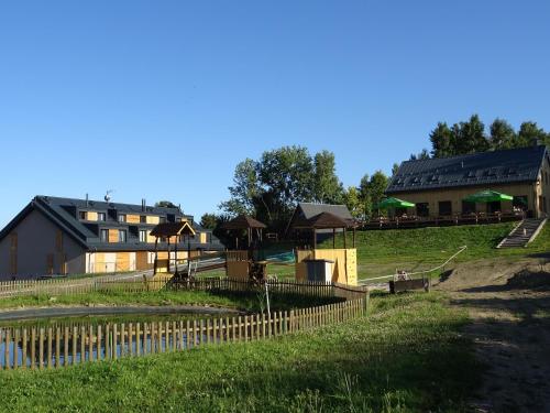 a farm with a fence and a building in the background at Apartmány Sport Dolní Morava in Dolní Morava