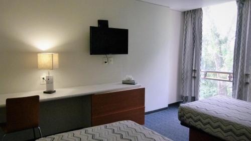 a hotel room with a bed and a desk with a television at Aristos Express CDMX in Mexico City