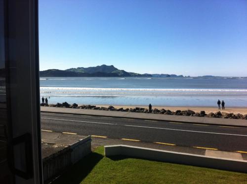 a view of a beach with people walking on the beach at Waterfront Apartments Whitianga in Whitianga