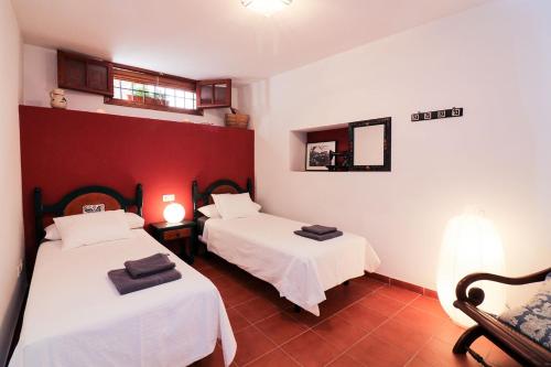 two beds in a room with red and white walls at Casa rural Llana 12 in Guadalupe