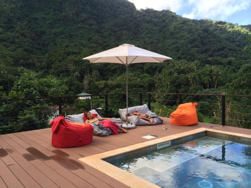 a couple of people laying on a deck next to a pool at La Villa Te Fetia Nui Moorea in Teavaro